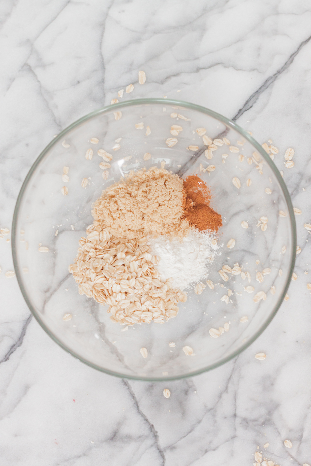 Rolled oats mixed with flour, cinnamon, and brown sugar in a bowl.